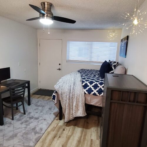 Apartment bedroom furnished with a desk, dresser, & twin bed